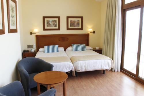 a hotel room with two beds and a chair at BLUESEA Gran Cervantes in Torremolinos