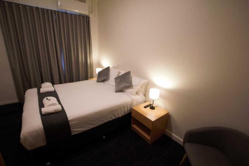 a hotel room with a bed and a table with a lamp at Sydney Junction Hotel in Hamilton