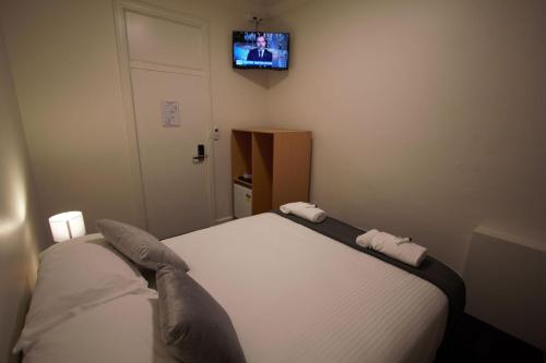 a bedroom with a bed with a tv on the wall at Sydney Junction Hotel in Hamilton