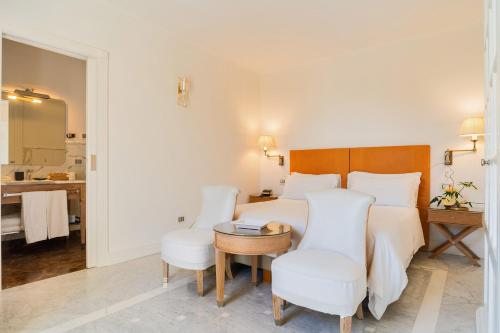 a hotel room with a bed and a table and chairs at Palazzo del Corso – Boutique Hotel in Gallipoli