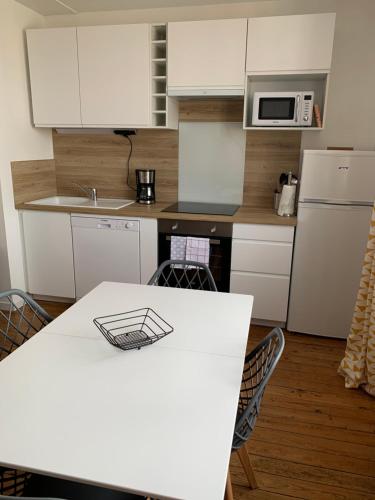 une cuisine avec des placards blancs et une table blanche avec des chaises dans l'établissement Le Phare de Cati, à Mers-les-Bains