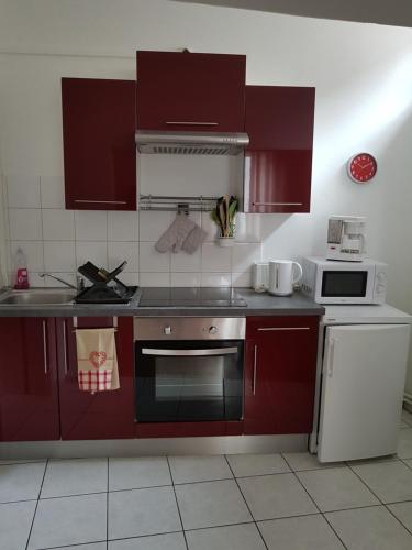 cocina con armarios rojos y fogones en appartement meublé romain, en Niederbronn-les-Bains