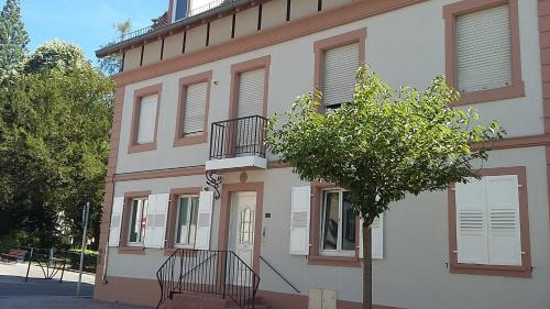 un edificio con un árbol delante de él en appartement meublé romain, en Niederbronn-les-Bains