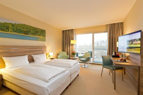 a hotel room with a bed and a desk and a television at Seehotel Fleesensee in Göhren-Lebbin