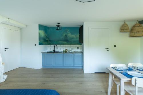 a kitchen with blue cabinets and a table at Apartamenty Na Klifie Przystań 18 Chłapowo in Władysławowo