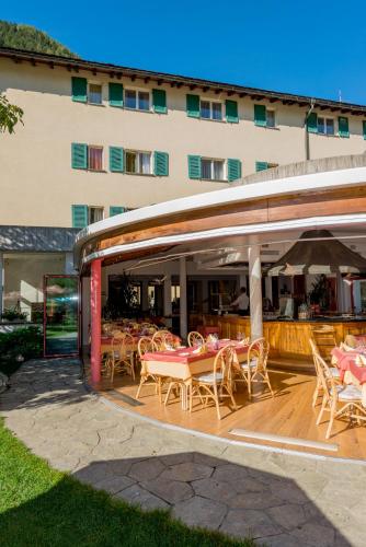 a patio with tables and chairs and a building at Hotel La Romantica in Le Prese, Poschiavo