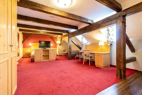 a living room with a red carpet and a room with a tv at Hotel Vollmann in Weilheim in Oberbayern
