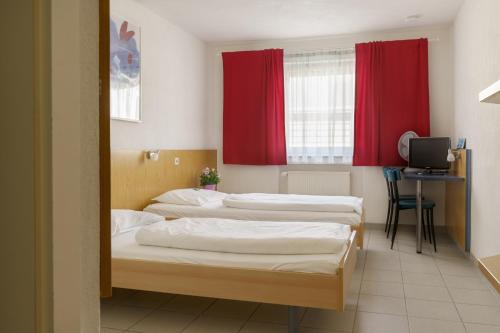 three beds in a room with red curtains at Motel Drei König- Ihr Transithotel in Heimsheim