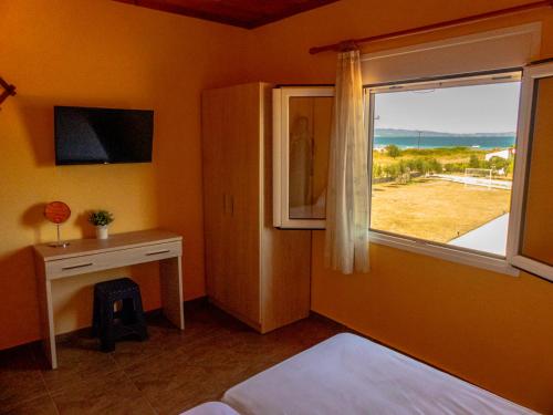 a bedroom with a bed and a window with a desk at Ktima Argiri in Ormos Panagias