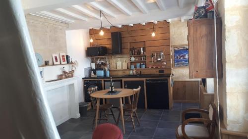 une petite cuisine avec une table et des chaises. dans l'établissement Maison Camille, à Port-en-Bessin-Huppain