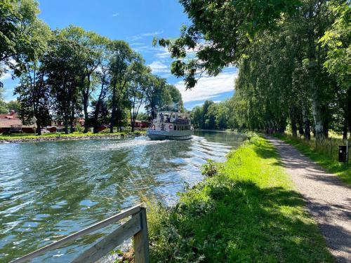 a boat is traveling down a river with trees at Liverpoolsstugan in Motala