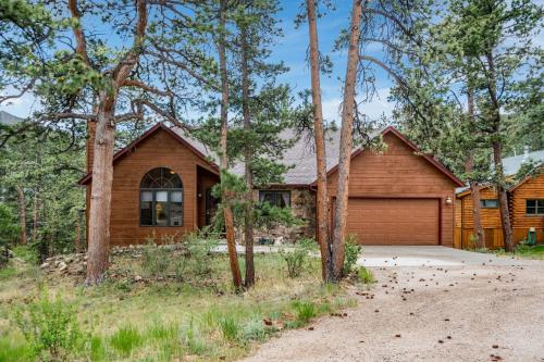 a wooden house with a garage in the woods at Heavenly Pines -- EV #3361 home in Estes Park