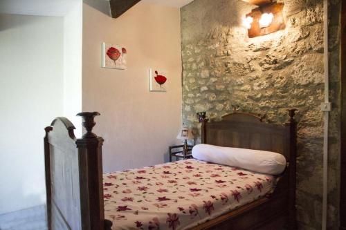 1 dormitorio con cama y pared de piedra en CHEZ SIMONE en Senouillac