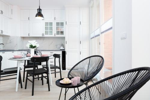 a kitchen with black chairs and a table with food on it at Apartamenty Rajska 8 - Gdańsk Stare Miasto by Renters in Gdańsk
