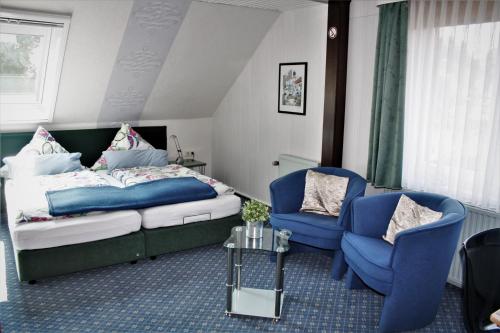 a bedroom with a bed and two blue chairs at Gästehaus Marek in Nordenham