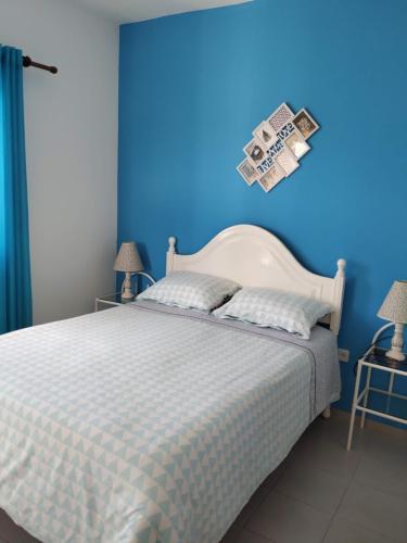 a bedroom with a white bed with a blue wall at Vivenda Familia Pedro in Vila do Bispo