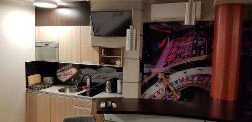 a small kitchen with a sink and a tv on the wall at Metropolis Apartamenty Centrum in Kalisz