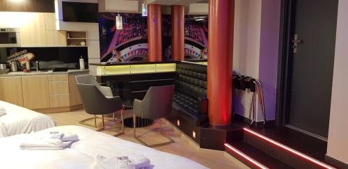 a room with a piano and some chairs and a kitchen at Metropolis Apartamenty Centrum in Kalisz
