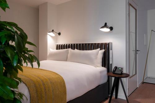 a bedroom with a white bed with a phone on a table at PREMIER SUITES Amsterdam in Amsterdam