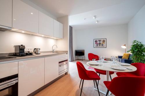 a kitchen and dining room with a table and red chairs at PREMIER SUITES Amsterdam in Amsterdam