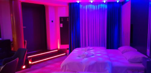 a bedroom with pink and blue lights and a bed at Metropolis Apartamenty Centrum in Kalisz