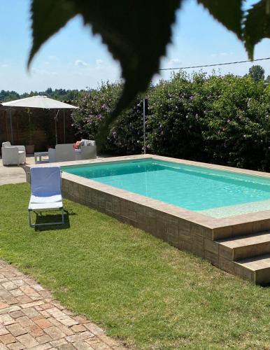 a swimming pool with a chair in the grass at B&B Locanda dei Tigli in Serravalle dʼAsti