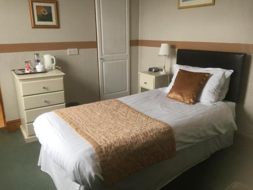 a hotel room with a bed and a dresser at Grove House Guest House in Telford