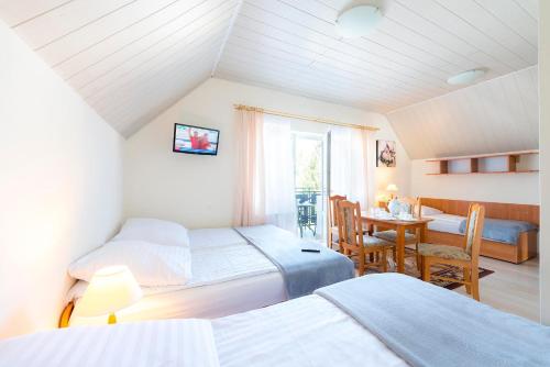 a bedroom with two beds and a desk and a table at Piramida Lux in Mrzeżyno