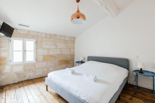 a bedroom with a white bed and a window at Appartement spacieux et lumineux avec climatisation et belle hauteur sous plafond - Halle 2EME in Castillon-la-Bataille