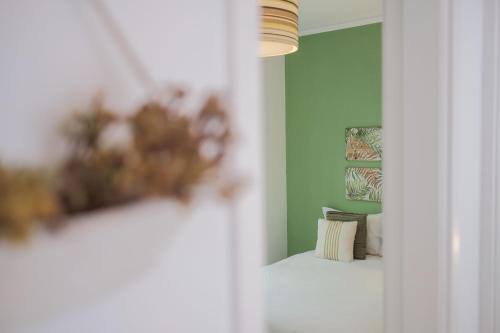een kamer met groene muren en een vaas met bloemen bij Casa do Zézêras in Nazaré