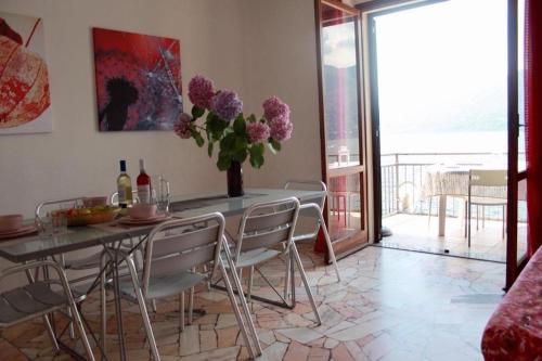 uma sala de jantar com uma mesa com cadeiras e flores roxas em Casa Spiaggia em Brezzo