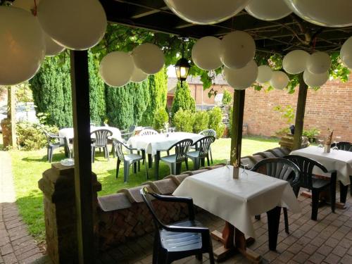 a restaurant with white tables and chairs under a pavilion at Mallories Formerly Kirkby House in Kirkby Mallory