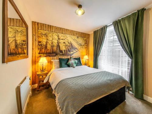 a bedroom with a bed with a painting on the wall at Deluxe Pirate's Cove Themed Apartment in St Austell