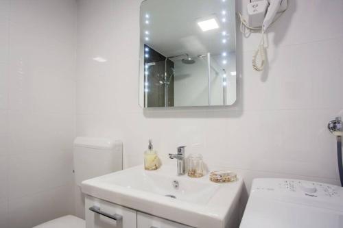 een witte badkamer met een wastafel en een spiegel bij Apartman Cone in Pula
