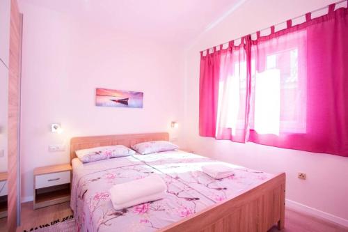een slaapkamer met een groot bed en roze gordijnen bij Apartman Cone in Pula