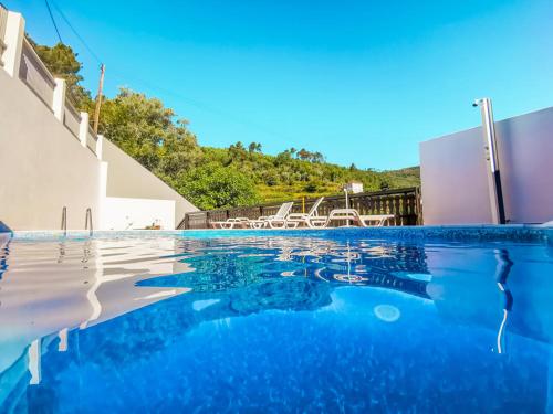 a swimming pool with blue water in front of a house at Casa Carolina in Vila Seca