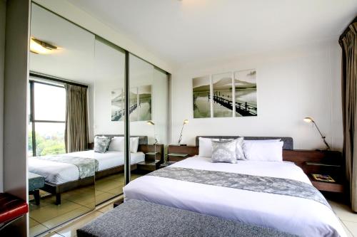 a hotel room with two beds and a mirror at The Nicol Hotel and Apartments in Johannesburg