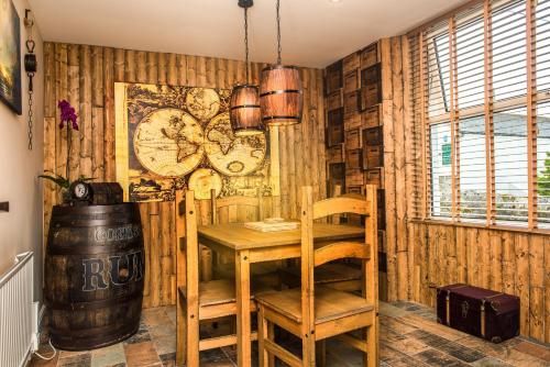 a dining room with a table and a clock on the wall at Deluxe Pirate's Cove Themed Apartment in St Austell