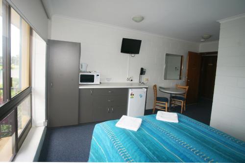 a kitchen with a refrigerator, microwave, sink and a table at Cedar Lodge Motel in Townsville