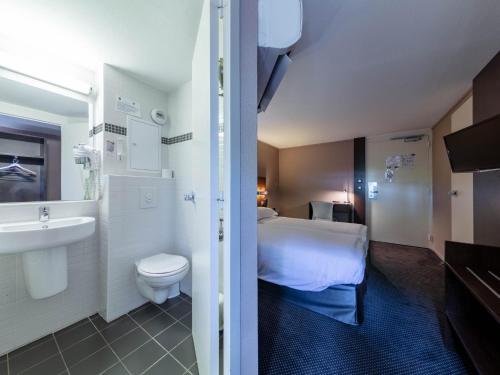 uma casa de banho com uma cama, um WC e um lavatório. em Noemys Valence Nord - hotel restaurant em Bourg-lès-Valence