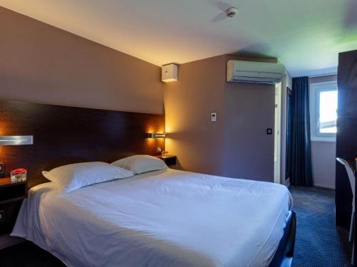 a hotel room with a large bed and a window at Noemys Valence Nord - hotel restaurant in Bourg-lès-Valence