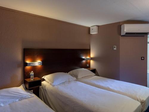 2 camas en una habitación de hotel con sábanas blancas en Noemys Valence Nord - hotel restaurant, en Bourg-lès-Valence