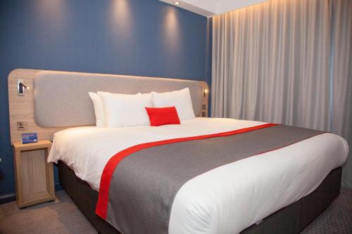 a bedroom with a large bed with a red pillow at Holiday Inn Express Cardiff Bay by IHG in Cardiff