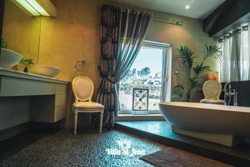 une salle de bain avec une grande baignoire et une fenêtre dans l'établissement Villa St Jean SUITE Romantique, à La Ciotat