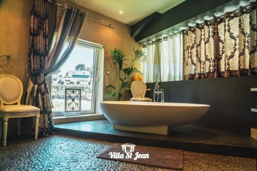 a bathroom with a large tub and a window at Villa St Jean SUITE Romantique in La Ciotat