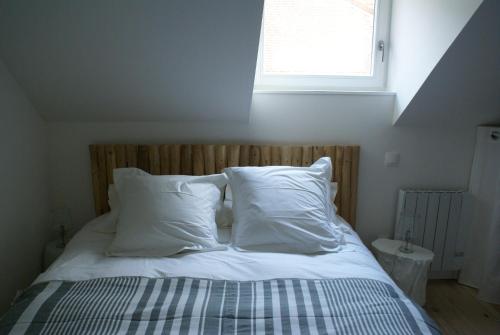 uma cama com almofadas brancas e uma janela num quarto em La Cour Soubespin em Lille