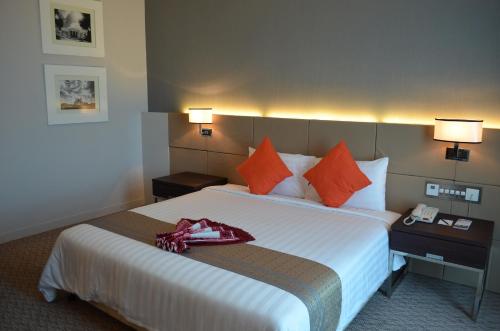 a hotel room with a large bed with orange pillows at Raia Hotel & Convention Centre Alor Setar in Alor Setar
