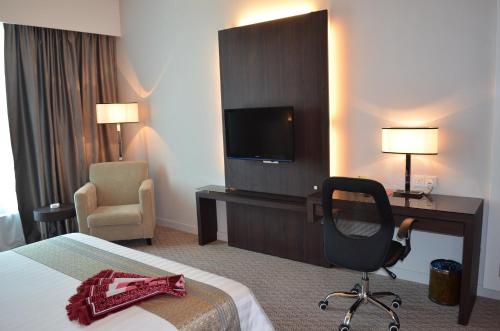 a hotel room with a bed and a desk and a chair at Raia Hotel & Convention Centre Alor Setar in Alor Setar