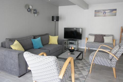 ein Wohnzimmer mit einem Sofa, Stühlen und einem TV in der Unterkunft Spa Apartment in Saint-Maurice