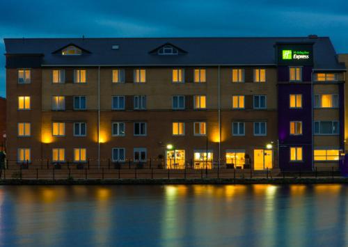 a building with a sign on it next to the water at Holiday Inn Express Cardiff Bay by IHG in Cardiff